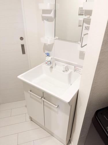 a white bathroom with a sink and a mirror at Palace Yokohama New & Private in Yokohama