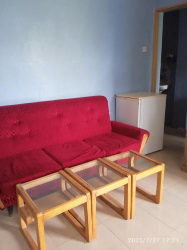 a red couch and two tables in a living room at Polycap Cottage Home in Murangʼa