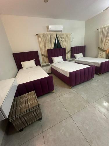 two beds in a room with purple furniture at Seaview Residency in Karachi