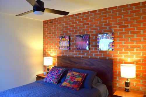 a bedroom with a brick wall and a bed with pillows at Kakaw's house, pool with a view of the 3 volcanoes in San Juan Alotenango