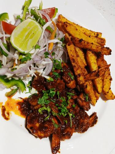 a plate of food with meat and a salad and fries at Resort Terra Paraiso Goa - A Beach Property in Calangute