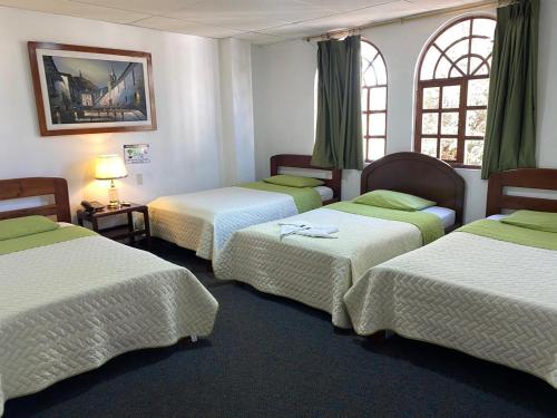 a room with four beds with green and white sheets at HOSTAL VISTA AMAZONAS in Quito