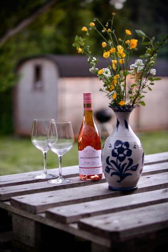 two wine glasses and a bottle and a vase with flowers at CentrumTrails in Ans