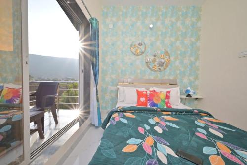 a bedroom with a bed with a floral bedspread and a balcony at ll EMPYREAN STAY ll LEONCINO VILLA ll 4BHK ll AC ll LONGEST PRIVATE POOL IN LONAVALA ll in Lonavala