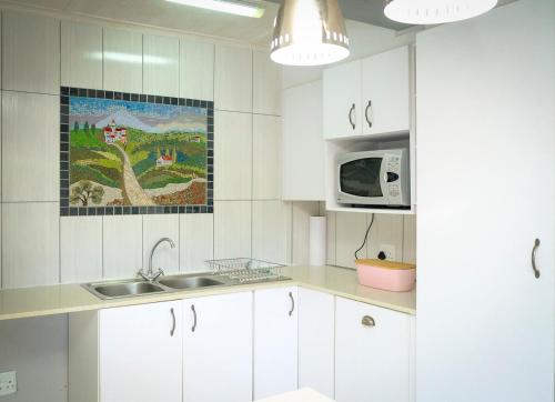 a white kitchen with a sink and a microwave at 2BR Retreat Near Game Reserve in Gqeberha