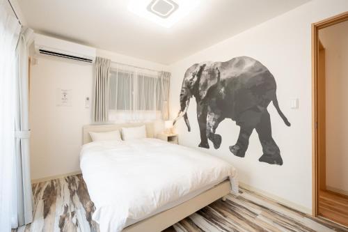 a bedroom with a bed and an elephant painting on the wall at Familia Kamata 2 in Tokyo