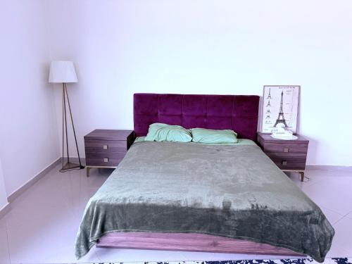 a bed with a purple headboard and two night stands at Campioni in Ajman 