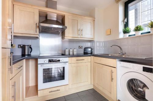 a kitchen with wooden cabinets and a washer and dryer at BnBNova - Tower Bridge - 1BR - St Paul's in London