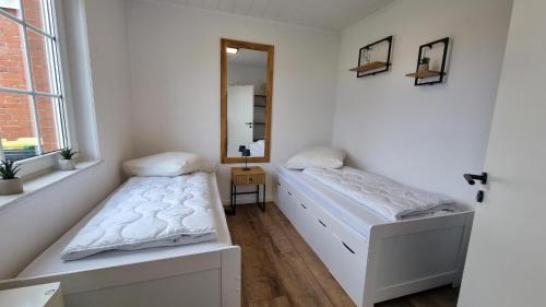 a bedroom with two beds and a mirror at Ferienhaus Friesenengel in Dornumersiel
