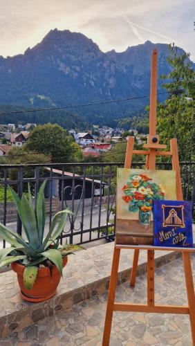 a painting and a chair on a balcony with a plant at Mont'Arte - Private Art retreat Villa in Buşteni