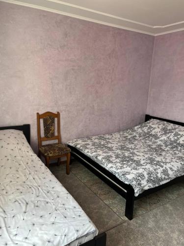 two beds sitting in a room with a chair at Smerichka in Zagorody