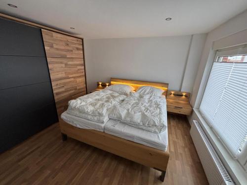 a bedroom with a bed with a wooden headboard at Ferienhaus Wellenperle in Dornumersiel