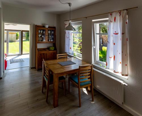 Un comedor con mesa y sillas y ventanas. en Ferienwohnung Muschel, en Dornum