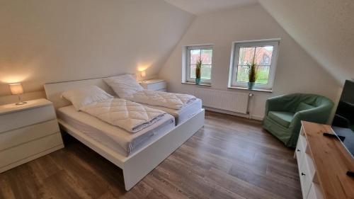 a bedroom with a bed and a green chair at Ferienhaus Pfeffermuschel in Neßmersiel