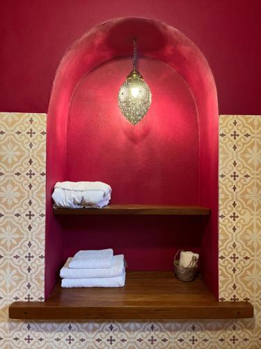 a bathroom with a red wall and a shelf with towels at Boutique Guesthouse Dar Zohra in Marrakech