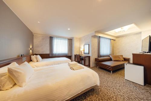 a large hotel room with two beds and a couch at Kokusai 21 International Hotel in Nagano