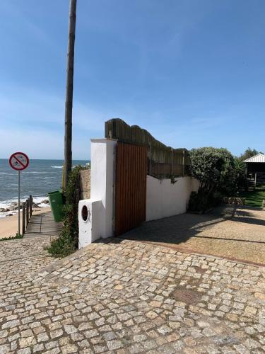 a building with a fence and a gate next to the beach at Beach house Estrela do Mar in Vila Chã