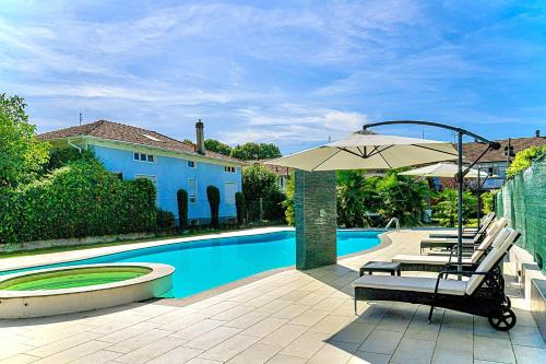 a patio with chairs and an umbrella next to a pool at Appartamento in villa con piscina privata e vasca idromassaggio ad uso esclusivo in Rivarolo Canavese