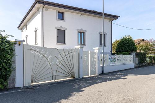 a white house with a gate and a fence at Appartamento in villa con piscina privata e vasca idromassaggio ad uso esclusivo in Rivarolo Canavese