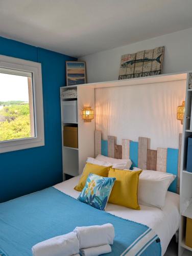 a bedroom with blue walls and a bed with yellow pillows at appartement T2 biscarosse plage in Biscarrosse-Plage