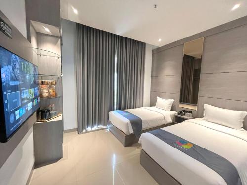 a hotel room with two beds and a flat screen tv at The Quadrant Hotel KNO in Medan