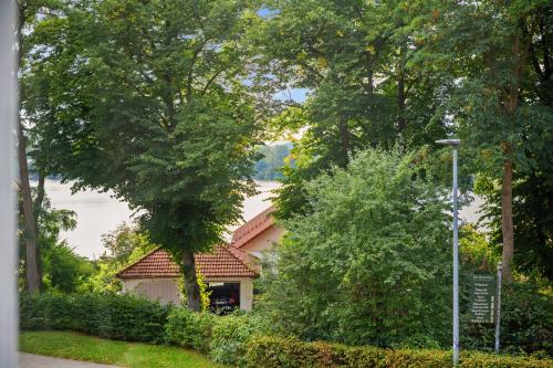a house in the midst of trees and bushes at MAISUITES Sperling - Zentrale Ferienwohnung mit Boxspringbett, Kaffeevollautomat, WLAN & seitlichem Seeblick in Mölln