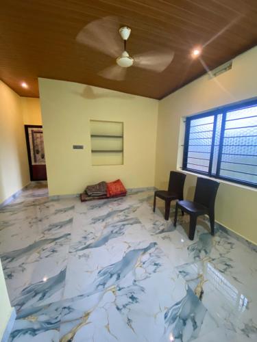 a room with a large marble floor with chairs and a ceiling at RDS Homestay in Honāvar