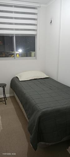 a bed in a white room with a window at Acogedor departamento en Villa Alemana in Villa Alemana
