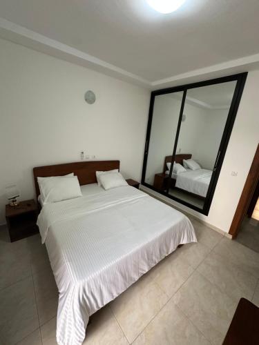 a bedroom with a large white bed and a mirror at 3 Appartements Indépendants - 1 ou 2 Chambres - Du Voyageur Solo au Groupe de 10 personnes - Résidence Calme, Proche Abidjan in Abidjan