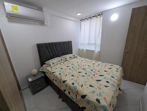 a bedroom with a bed with a comforter and a window at Apartment in the center of Cali, 2nd Floor in Cali