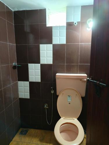 a bathroom with a toilet and a tile wall at Mary's Aparts in Cochin
