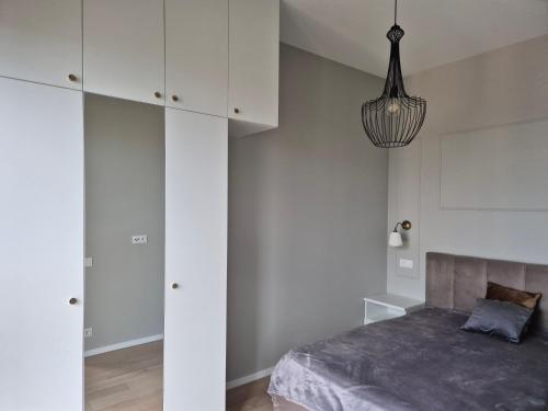 a bedroom with a bed and a chandelier at Apartament Hanza Tower 13th floor with balcony in Szczecin