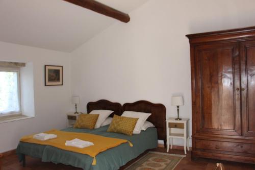 Un dormitorio con una cama y un armario de madera. en Le Bastidon, gîte des Lucioles en Provence, en Montségur-sur-Lauzon