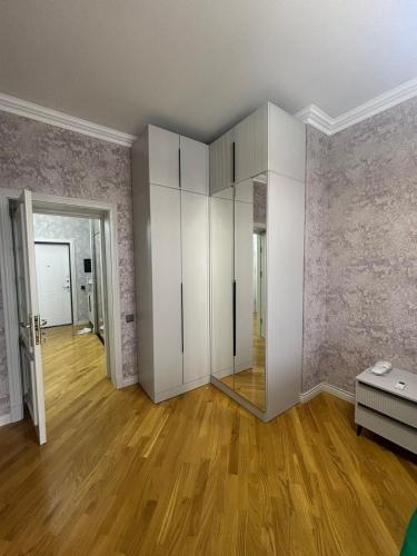 Una sala de estar vacía con gabinetes blancos y pisos de madera. en CozyOneBedroom, en Baku