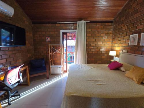 ein Schlafzimmer mit Bett, Schreibtisch und Fernseher in der Unterkunft Casa Equipada e Confortável p seu Lazer em Gravatá in Gravatá