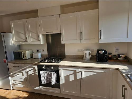 a kitchen with white cabinets and a stove top oven at Double Bedroom in Dartford central- Private Toilet & Bathroom in Dartford