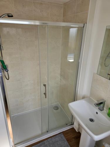 a shower with a glass door next to a sink at Double Bedroom in Dartford central- Private Toilet & Bathroom in Dartford