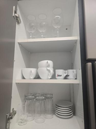 a shelf with dishes and cups and plates in a kitchen at Lazuli Urban Luxury -2 bedroom with Pool in Larnaka