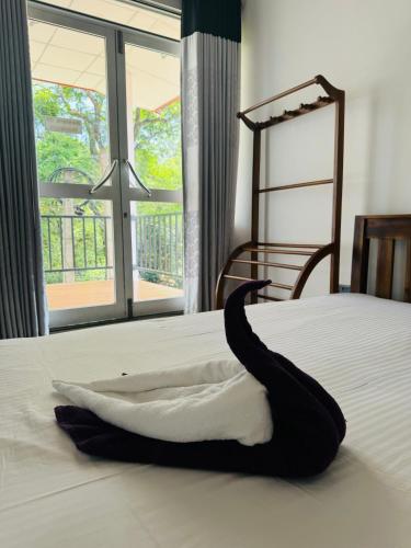 a black object on a white bed with a window at Nature park hotel in Polonnaruwa