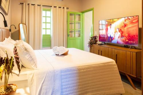 a bedroom with a white bed and a flat screen tv at Casa Jaú in Novo Airão