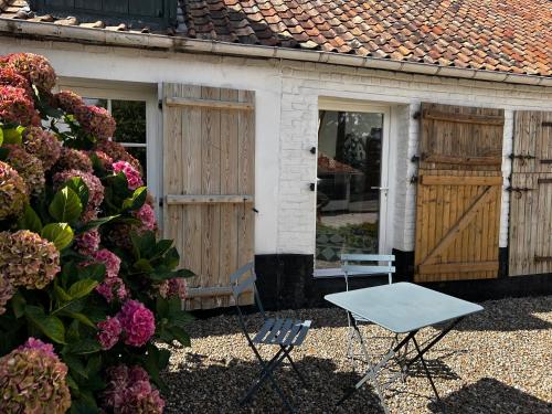 a table and a chair in front of a house at La Bergerie - Chambres d'hôtes entre terre et mer in Recques-sur-Course