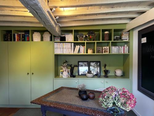 a room with green shelves and a table with flowers at La Bergerie - Chambres d'hôtes entre terre et mer in Recques-sur-Course