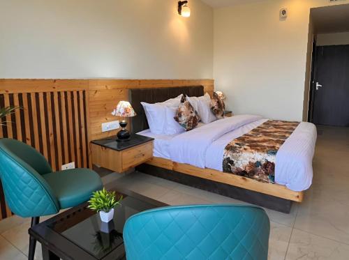 a bedroom with a large bed and a blue chair at Pinerock Resort ! Luxury! Mountain View! Open Terrace ! Cafeteria in Mussoorie