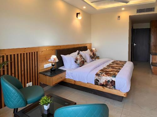 a bedroom with a large bed and a blue chair at Pinerock Resort ! Luxury! Mountain View! Open Terrace ! Cafeteria in Mussoorie