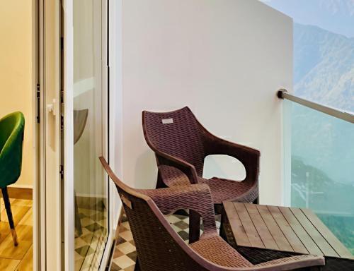 a wicker chair sitting next to a table on a balcony at The Pine Woods A Luxury Resort in Mussoorie Rooftop Restro in Mussoorie