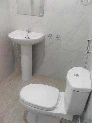 a white bathroom with a toilet and a sink at Mayon Guest in Tangalle