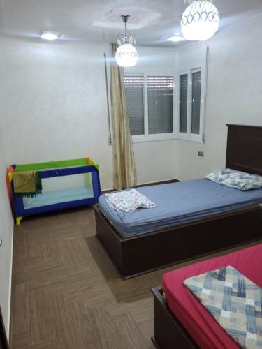 a bedroom with two beds and a window and chandeliers at appartement NADOR wifi gratuit clima mobile in Nador