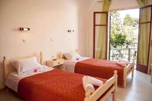 two beds in a room with a window at Maria's Apartments in Kavos