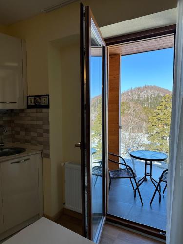 a kitchen with a table and a balcony with a table and chairs at The Valley Bakuriani in Bakuriani