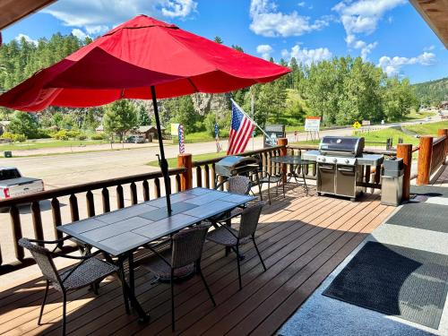 a picnic table with an umbrella and a grill on a deck at Mountain View Lodge & Cabins in Hill City